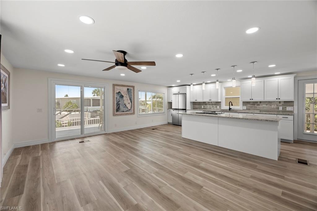 Image 2: Kitchen featuring open floor plan, hanging light fixtures, white cabinetry, tasteful backsplash, and a center island