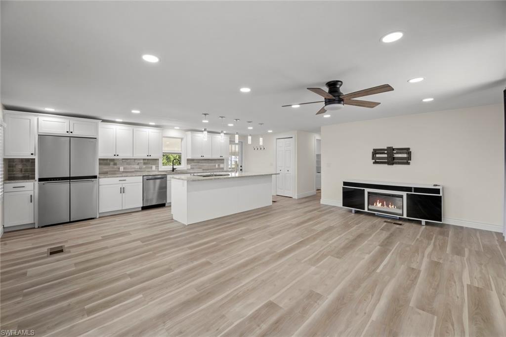 Image 3: Kitchen with open floor plan, white cabinetry, recessed lighting, a kitchen island, and appliances with stainless steel finishes