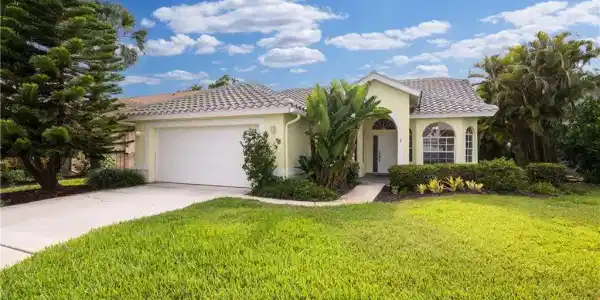 Image 2: Single-story residence featuring a tile roof, light-toned exterior, arched windows, and an attached two-car garage