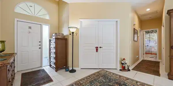 Image 3: Foyer featuring light-toned tile flooring, a half-round transom window, and a vaulted ceiling