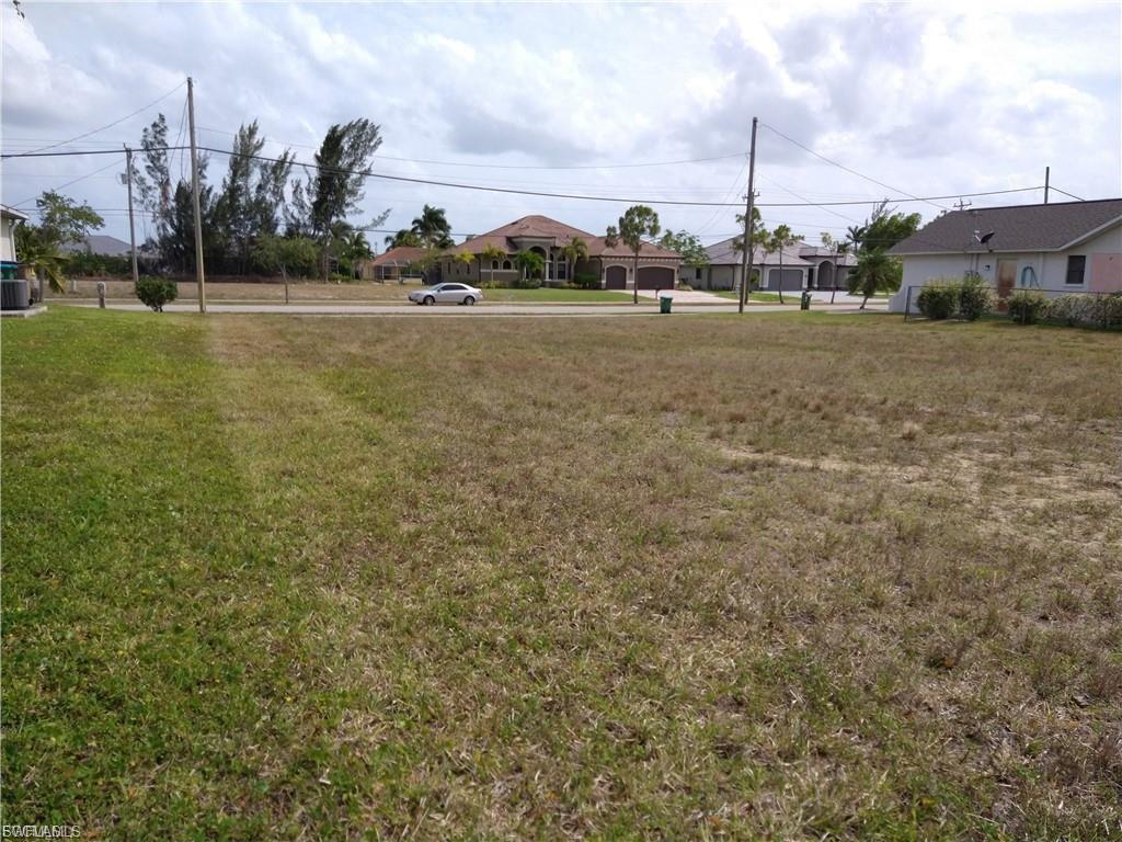Image 2: Expansive lot with partial grass coverage, featuring a clear building envelope, established street frontage, and overhead utilities present