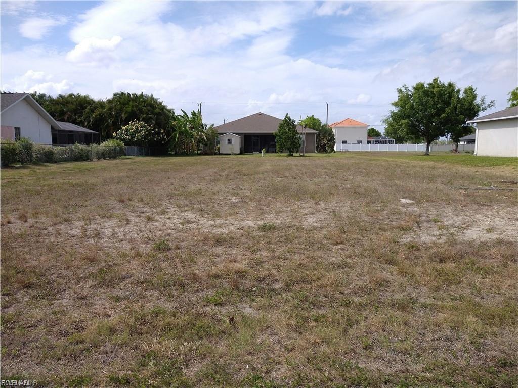 Image 3: Expansive lot with partial grass coverage, surrounded by existing residential structures