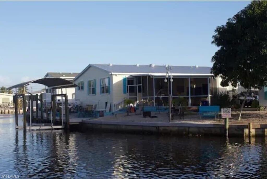 Image 1: Rear view of property featuring a water view and a sunroom