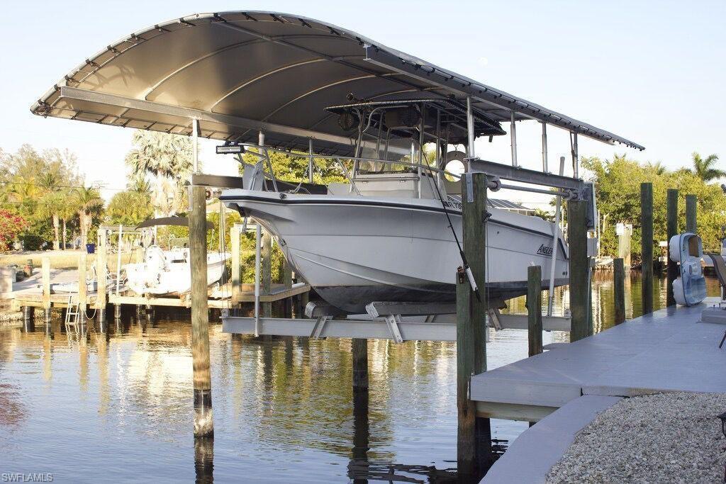 Image 2: Dock featuring boat lift and a water view