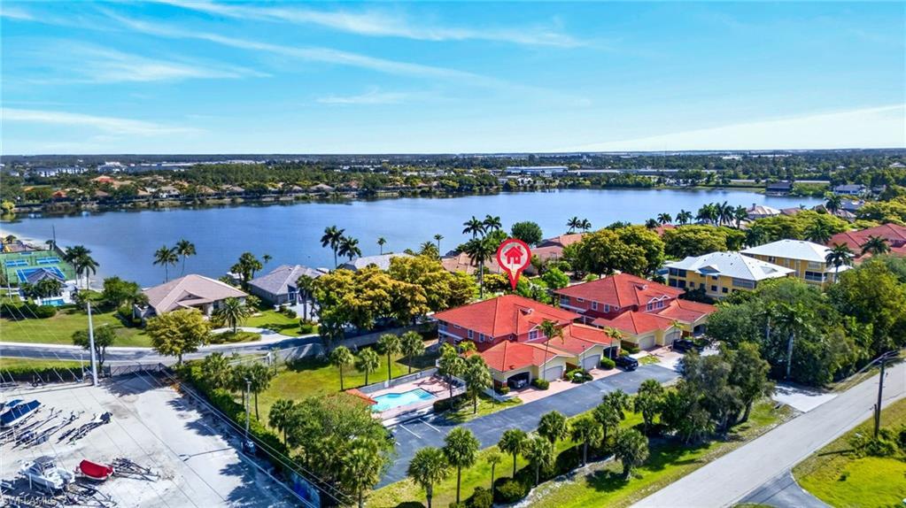 Image 2: Aerial perspective showcasing the property with a red tile roof and a private pool, set against a large body of water