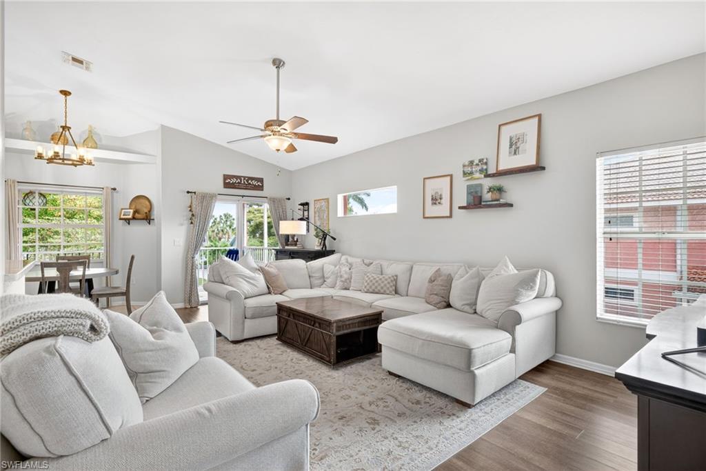 Image 4: Spacious living area featuring vaulted ceilings, wood-finish flooring, and a ceiling fan with integrated lighting