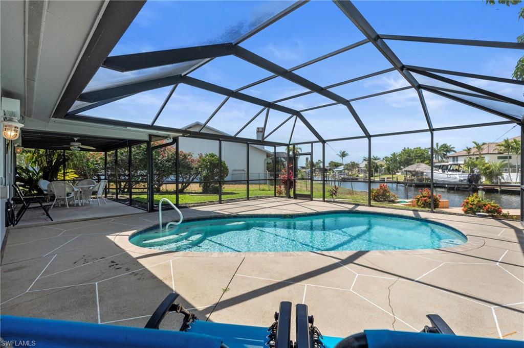 Image 2: Swimming pool featuring a water view, a patio, a sunroom, and glass enclosure
