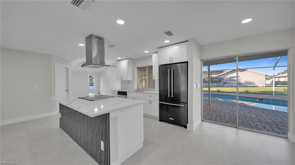 Image 3: Kitchen featuring black appliances, light stone countertops, white cabinetry, island exhaust hood, and a center island
