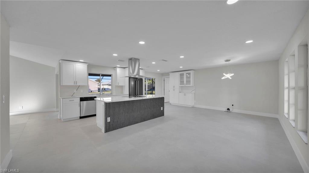 Image 4: Kitchen featuring white cabinetry, a kitchen island, dishwasher, light stone countertops, and open floor plan