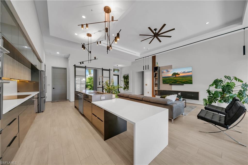 Image 2: Open-concept kitchen and living area featuring light wood-finish flooring