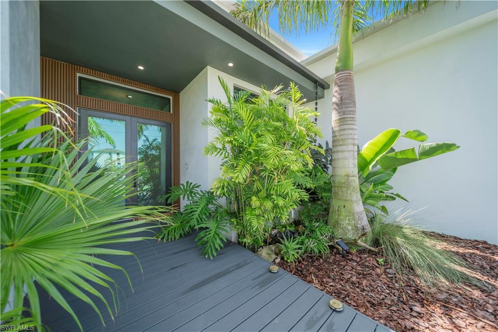 Image 3: Entryway featuring a dark composite decking path leading to double glass doors with transom windows