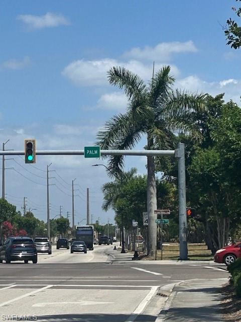Image 2: View of road featuring traffic lights, sidewalks, traffic signs, and curbs