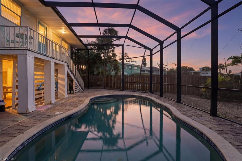 Image 2: Pool at dusk with large screened in lanai and oversized private backyard - Virtually Edited Image