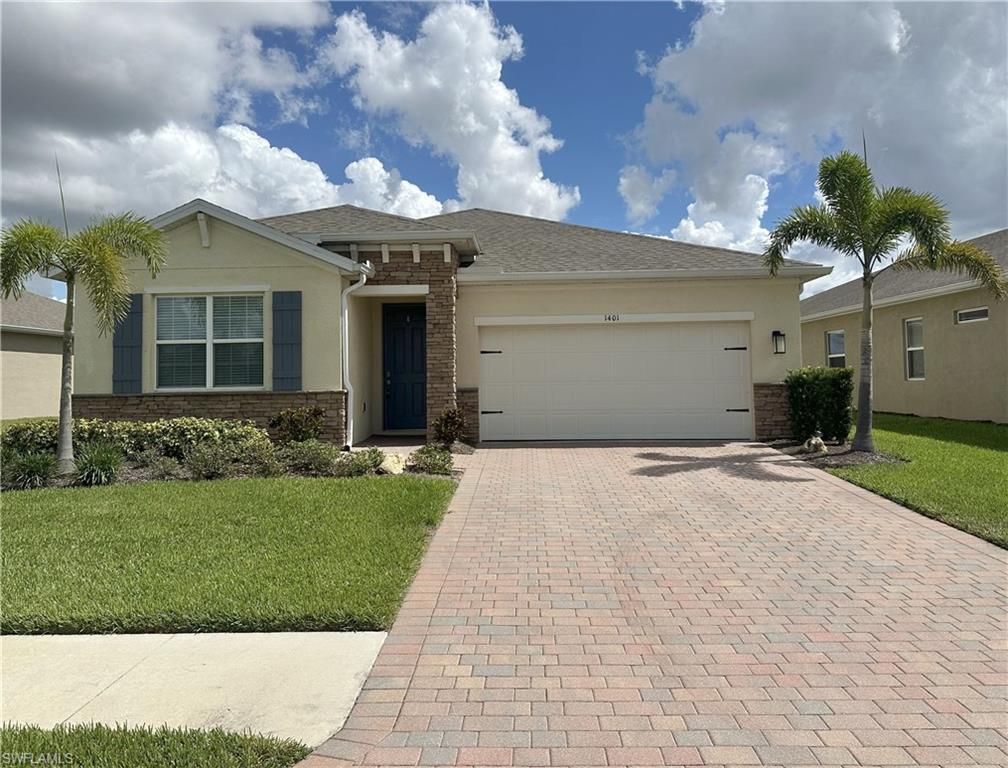 Image 2: View of front facade with a front yard, decorative driveway, stucco siding, and an attached garage