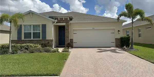 Image 2: View of front facade with a front yard, decorative driveway, stucco siding, and an attached garage