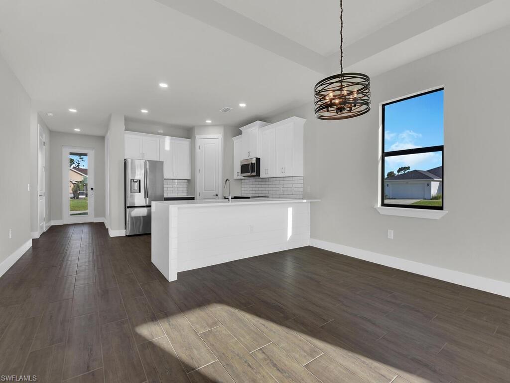 Image 3: Kitchen featuring healthy amount of natural light, a peninsula, white cabinetry, dark wood-style flooring, and recessed lighting