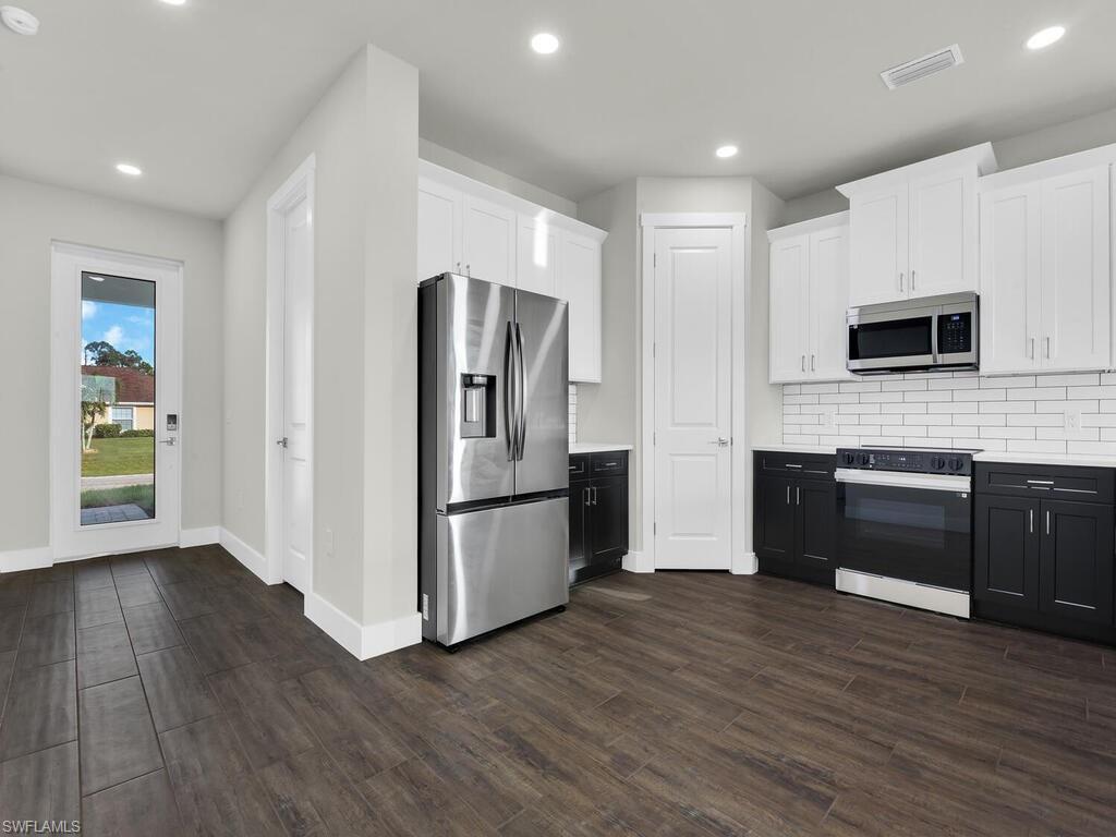 Image 4: Kitchen with white cabinetry, appliances with stainless steel finishes, tasteful backsplash, recessed lighting, and dark wood-type flooring