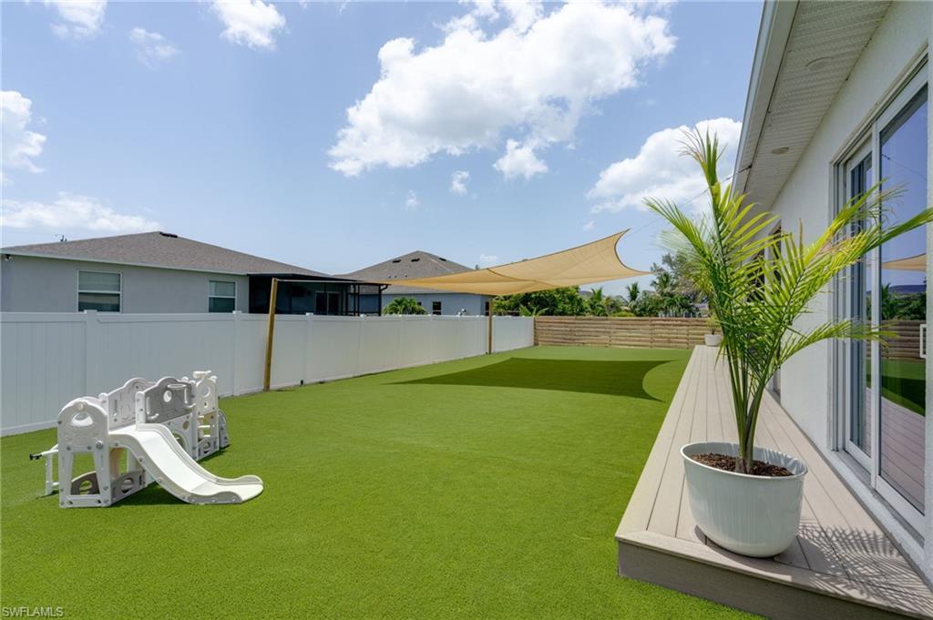 Image 3: Expansive backyard featuring synthetic turf, a privacy fence, and a sun sail shade structure