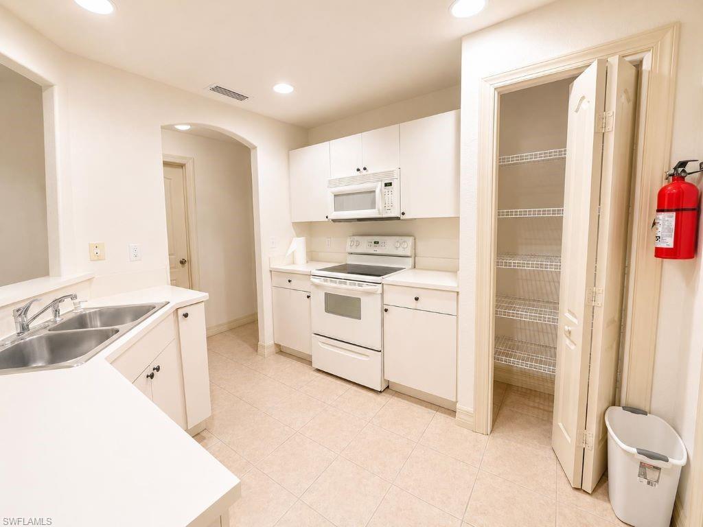 Image 3: Neutral-toned kitchen featuring white cabinetry, a built-in microwave, a double-basin stainless steel sink, and a pantry with wire shelving
