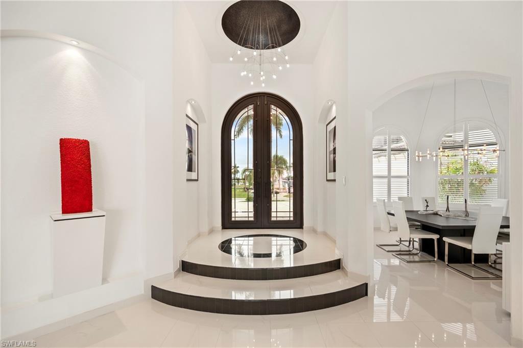 Image 3: Foyer entrance with french doors, arched walkways, a chandelier, and a high ceiling