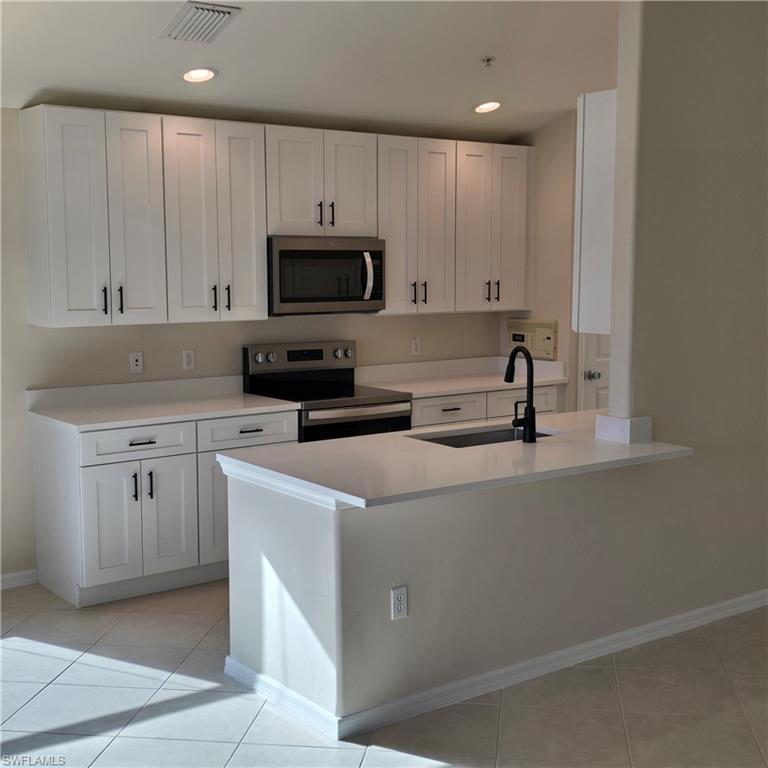 Image 4: Kitchen featuring white cabinetry, appliances with stainless steel finishes, light tile patterned flooring, and recessed lighting