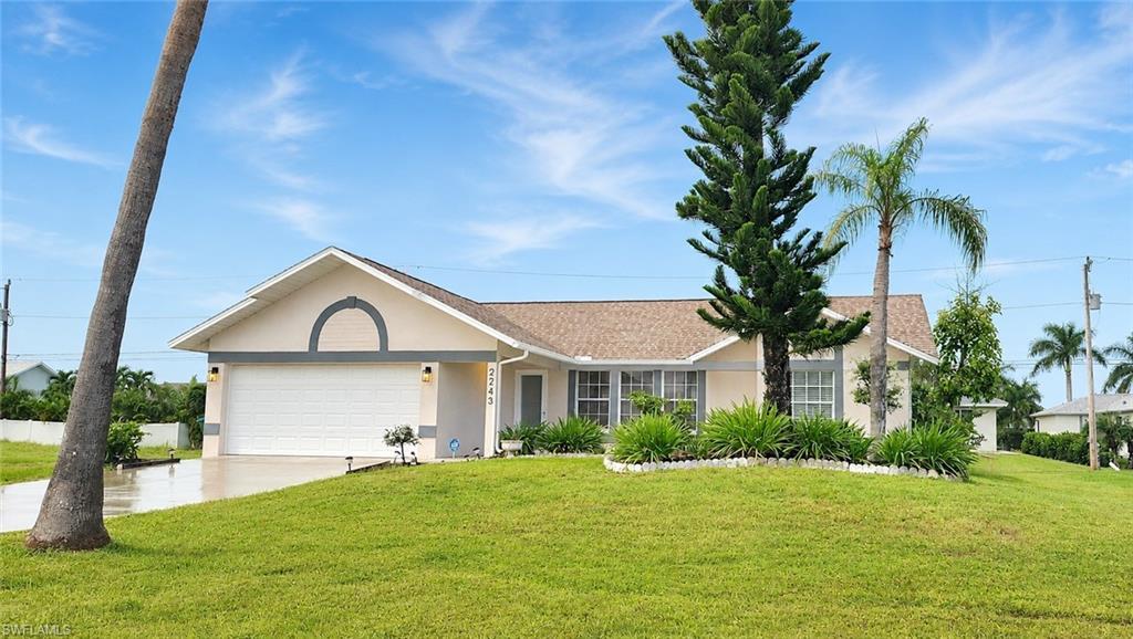 Image 1: Contemporary single-story residence featuring a two-car garage, mature landscaping, and an inviting front yard with a palm tree