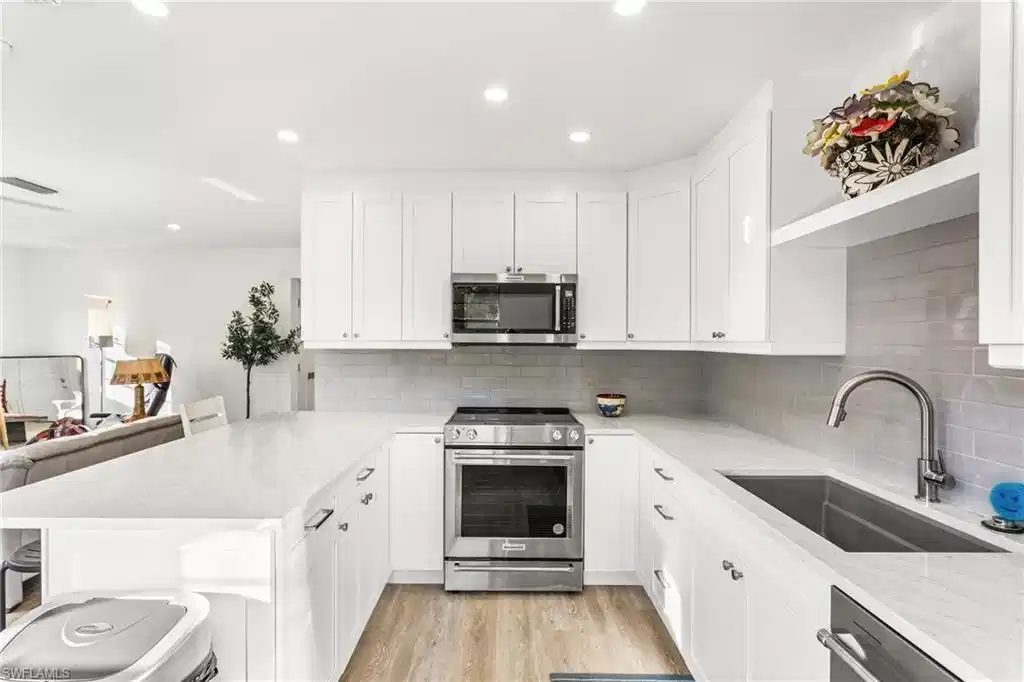 Image 1: Kitchen featuring appliances with stainless steel finishes, light stone countertops, a breakfast bar area, white cabinets, and a peninsula