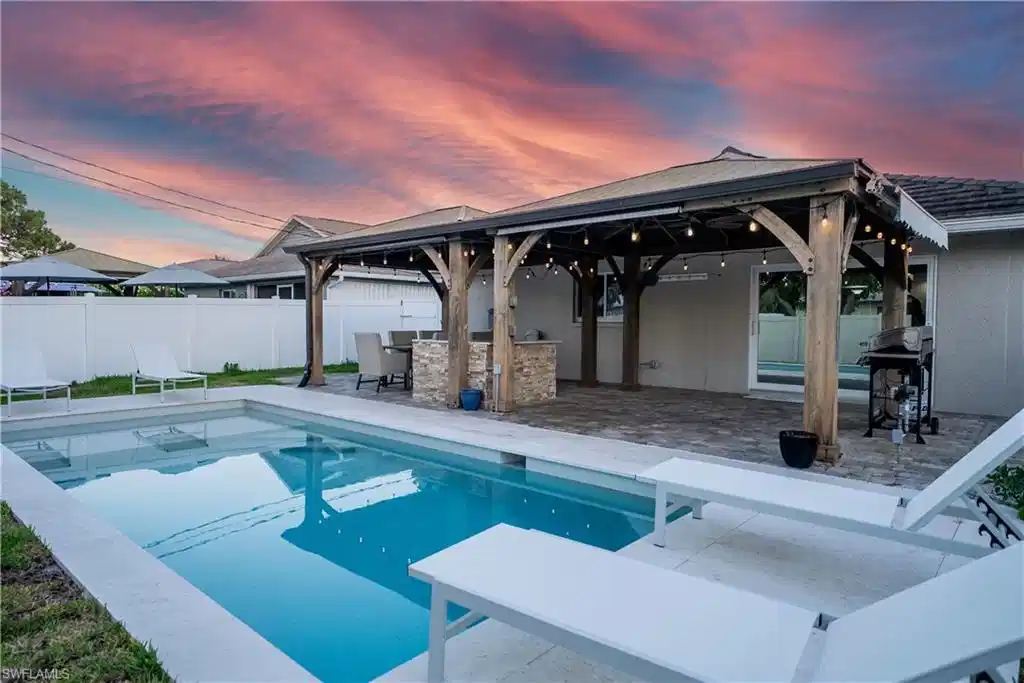 Image 1: Pool at dusk featuring a gazebo, a fenced backyard, grilling area, and a patio