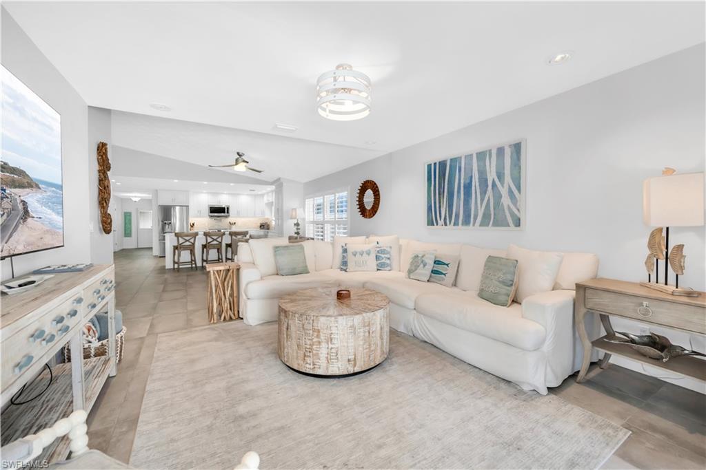 Image 2: Living room with a ceiling fan, lofted ceiling, and light tile patterned floors