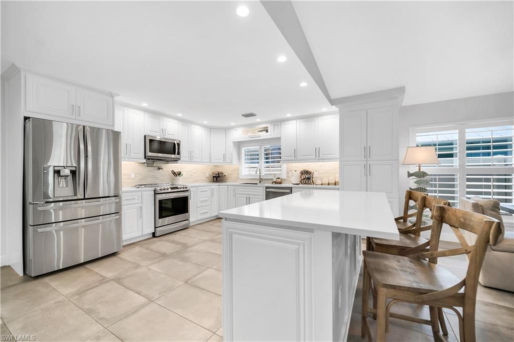 Image 3: Kitchen with stainless steel appliances, light countertops, backsplash, recessed lighting, and a sink