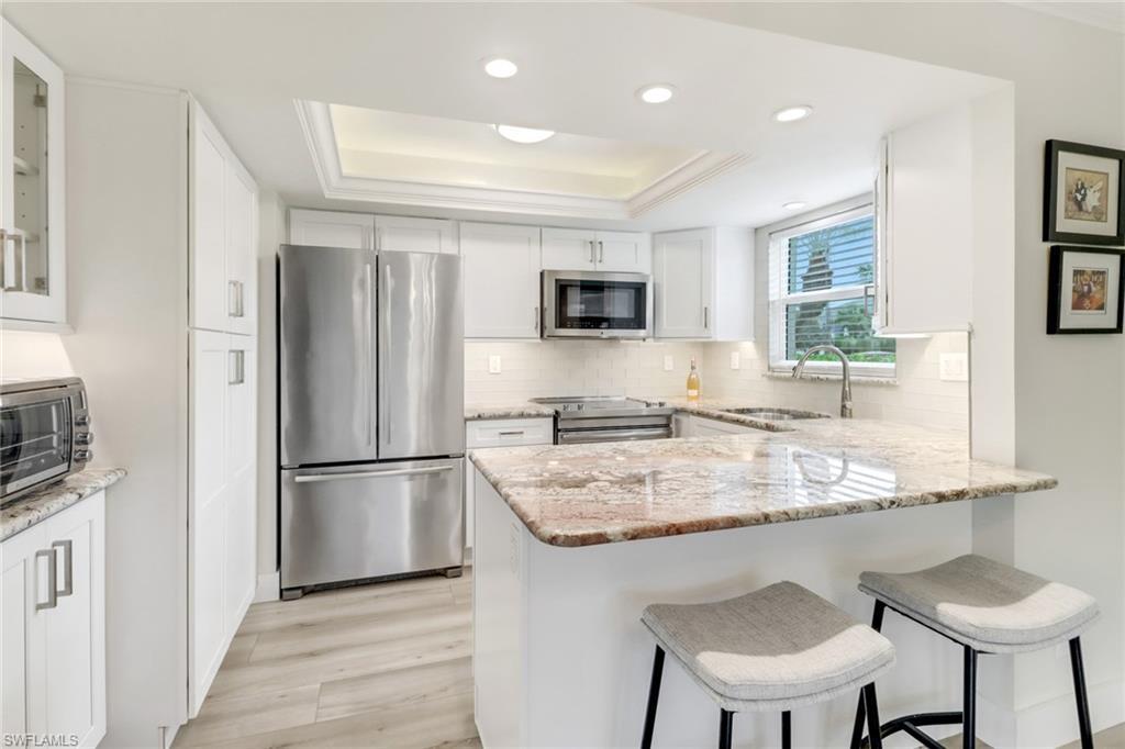 Image 4: Kitchen featuring sink, white cabinets, a raised ceiling, and stainless steel appliances
