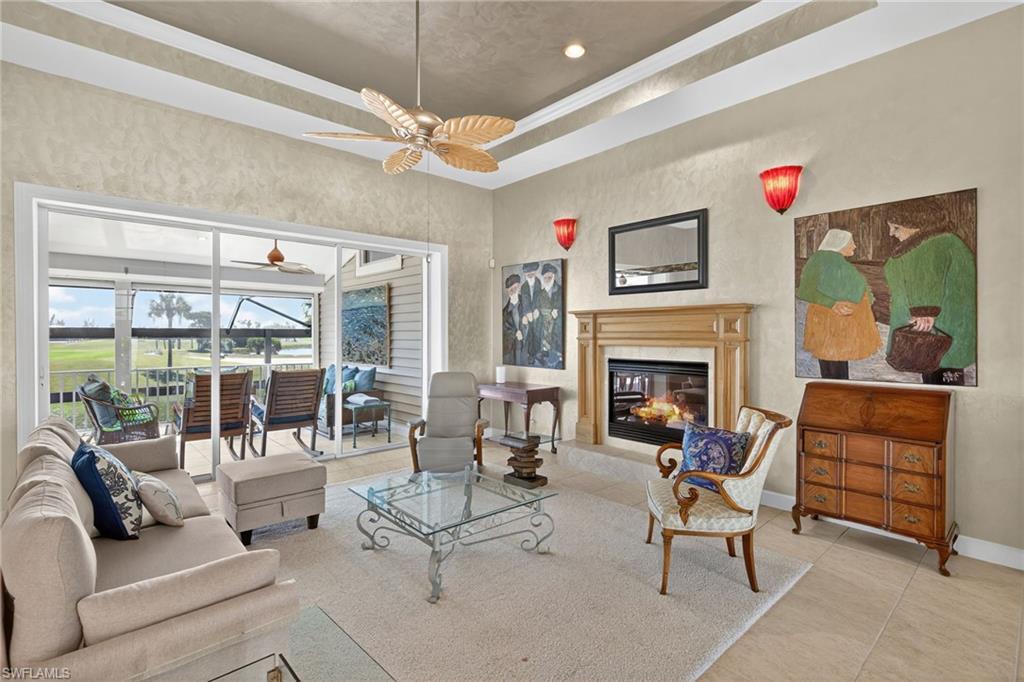 Image 3: Tiled living area featuring a raised ceiling, a premium fireplace, crown molding, a sunroom, and recessed lighting