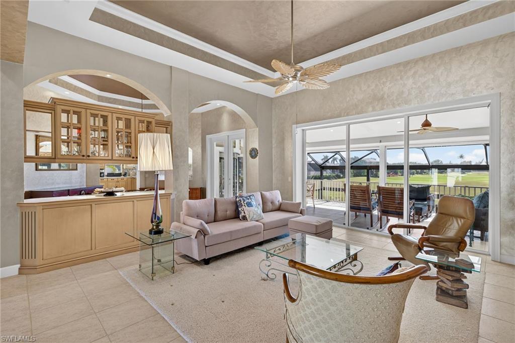 Image 4: Living area featuring a tray ceiling, light tile patterned flooring, and a sunroom