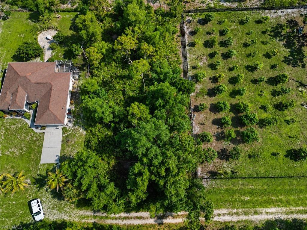 Image 3: Expansive property featuring a single-story residence with a brown shingle roof, a concrete driveway, and a screened patio area