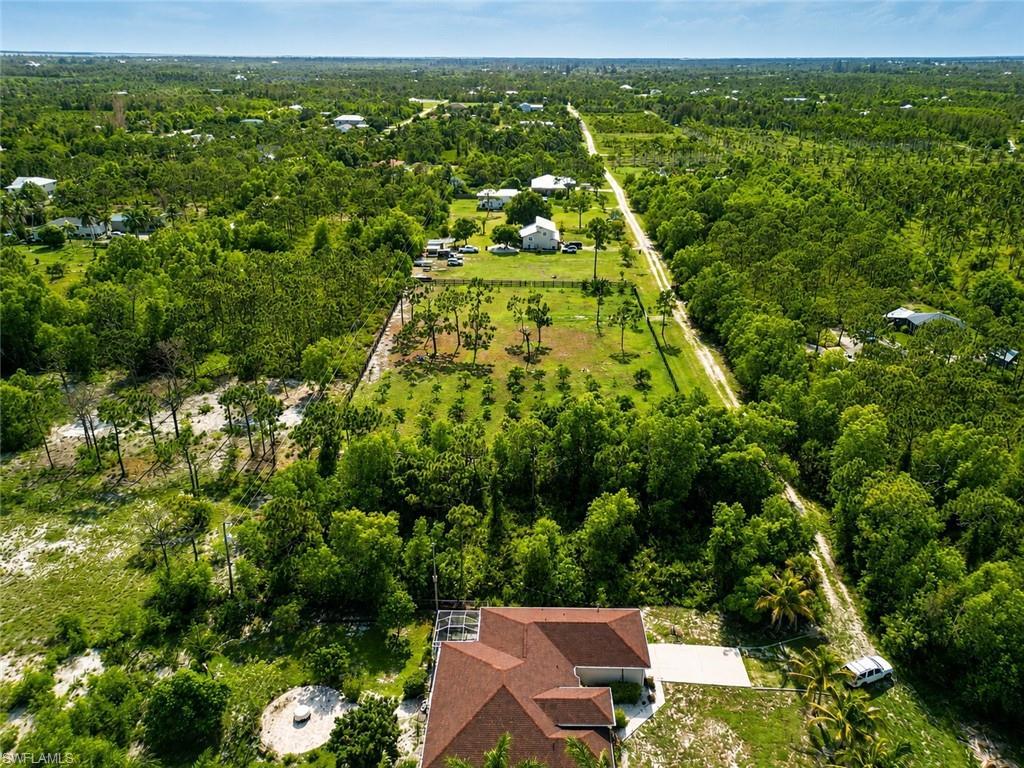 Image 4: Expansive aerial perspective showcasing a property with a distinct red-tiled roof and a light-colored driveway