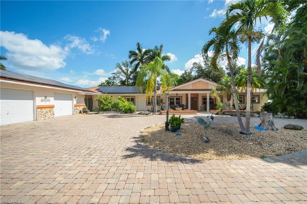 Image 3: Ranch-style house featuring roof mounted solar panels, an attached garage, curved driveway, stone siding, and stucco siding