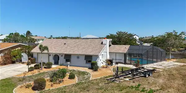 Image 3: View of front of house featuring glass enclosure, a front lawn, concrete driveway, and an outdoor pool
