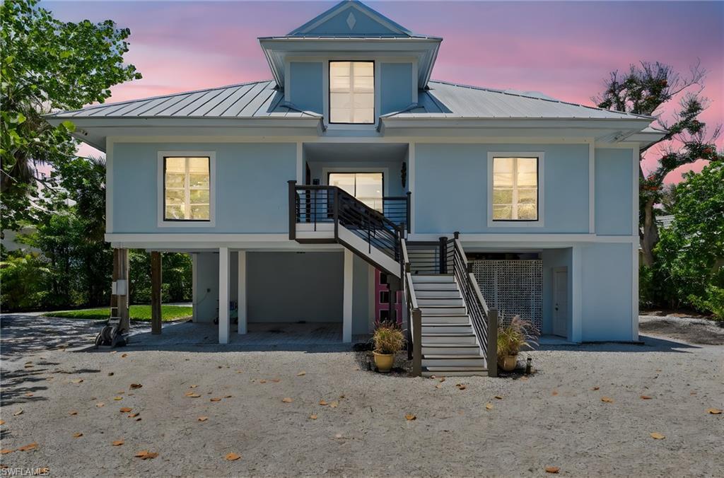 Image 3: View of front facade with a metal roof, a carport, stairway, and driveway
