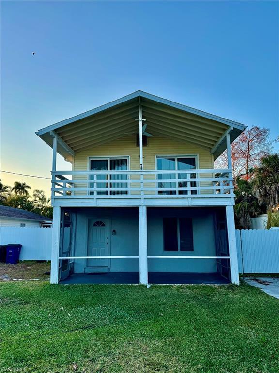 Image 2: Back of house at dusk featuring a balcony and stucco siding