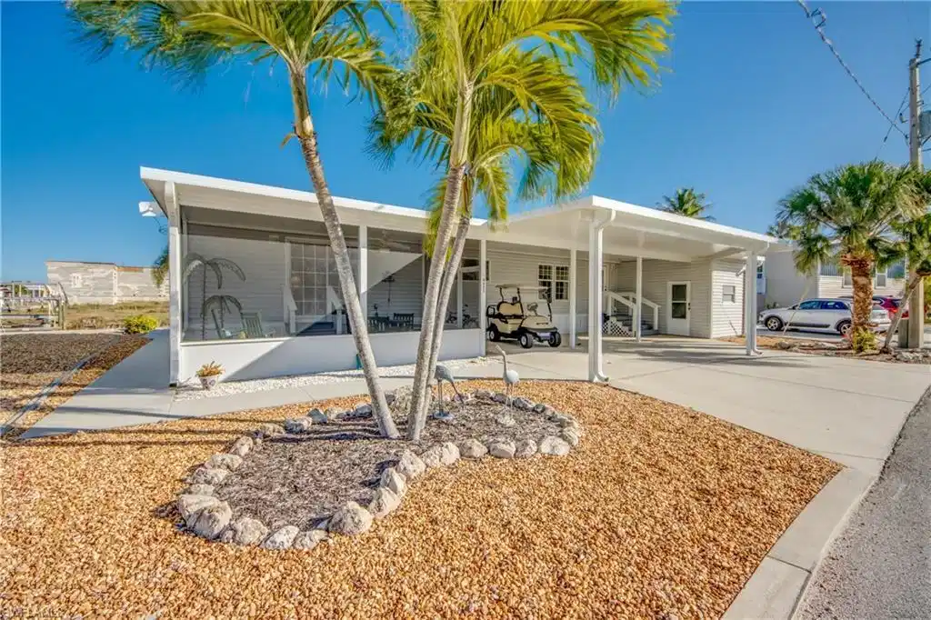 Image 1: Back of house with an attached carport, concrete driveway, and a sunroom