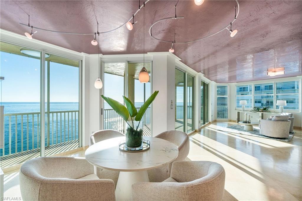 Image 2: The waterfront dining area feels like a postcard perfect Sunroom highlighted by a rich custom Venetian plaster ceiling,  functional & beautiful contemporary track lighting, a water view, and expansive windows with Southern golf waterfront views in two directions.