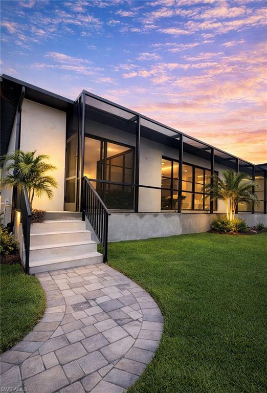 Image 3: Back of property featuring a lawn, stucco siding, a patio area, and a lanai (Rendered photo)