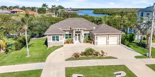 Image 3: View of front facade with a front lawn, a water view, concrete driveway, a garage, and roof with shingles