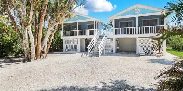 Image 2: View of front of house with gravel driveway, an attached garage, and a sunroom
