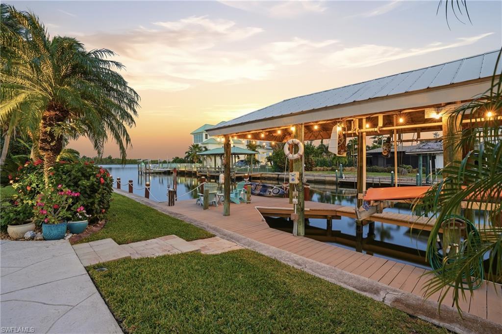 Image 3: Dock featuring boat lift, a water view, and a yard -Virtually enhanced image