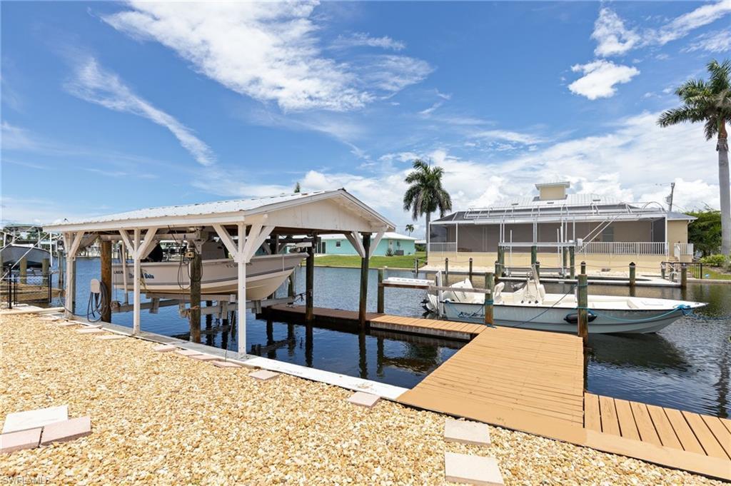 Image 4: Waterfront property featuring a covered boat lift, an additional boat slip, a wooden dock, and a gravel-covered bank