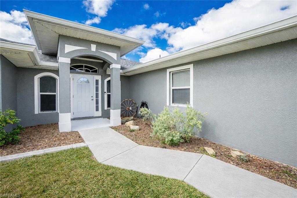 Image 2: View of exterior entry with stucco siding and a yard