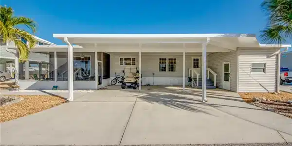 Image 2: Rear view of property featuring a carport, driveway, and entry steps
