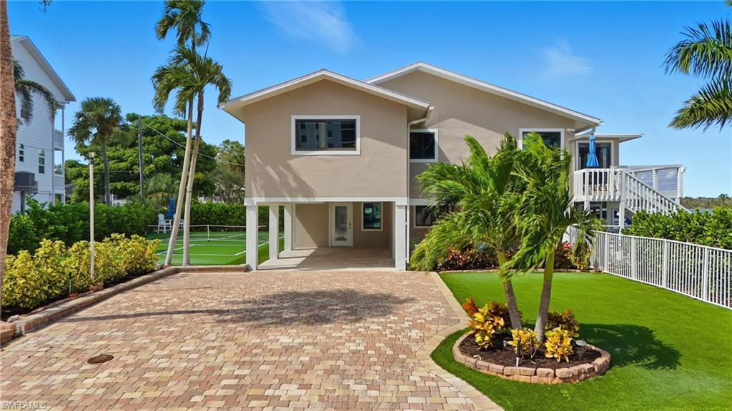 Image 4: Coastal inspired home featuring stucco siding, a carport, and decorative driveway - Virtually Edited Image