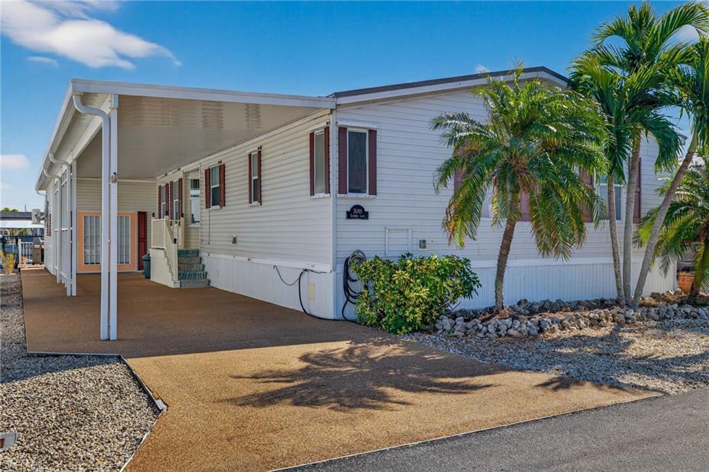 Image 1: View of front facade with a carport and driveway
